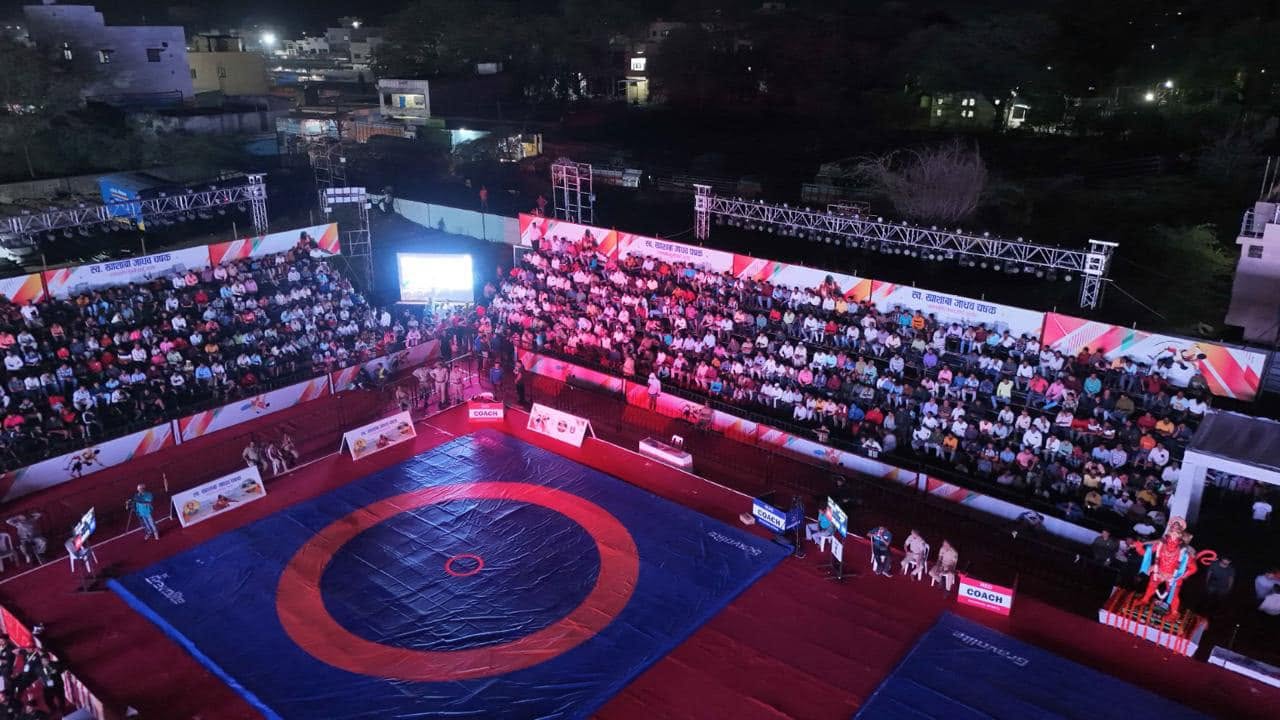 Ground-level view of wrestling match in progress under spectator gallery