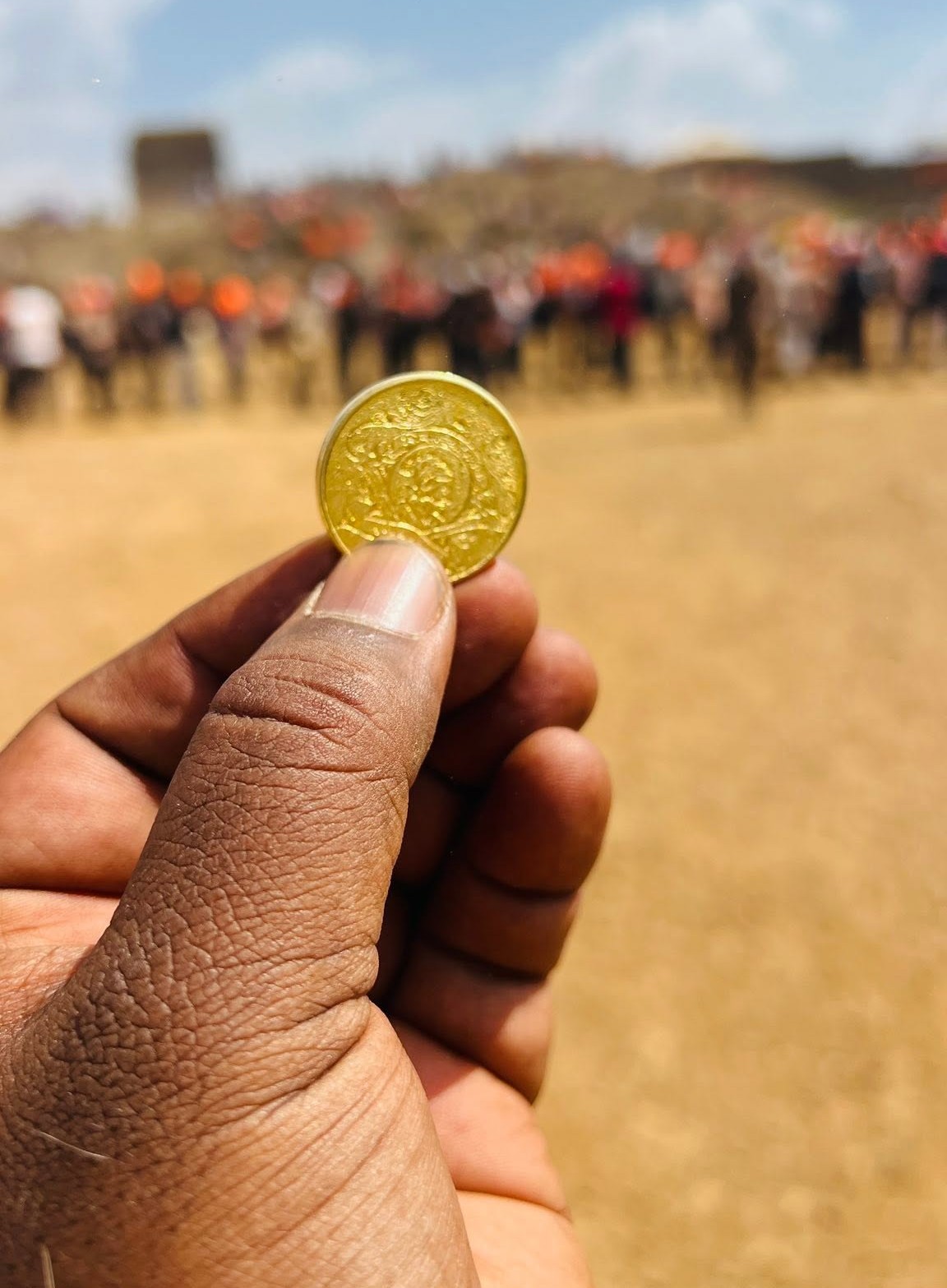The Shivrajyabhishek Hon commemorative coin held up against the crowd at Raigad Fort